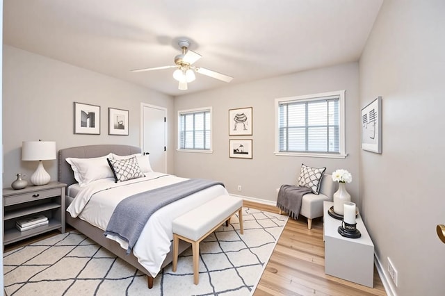 bedroom with light wood-type flooring, ceiling fan, and baseboards