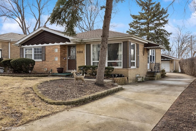 view of front facade featuring brick siding, a shingled roof, an outbuilding, and a garage