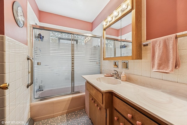 bathroom with combined bath / shower with glass door, tile walls, vanity, and tile patterned floors