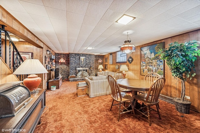 dining space with stairway, a fireplace, wood walls, and carpet floors