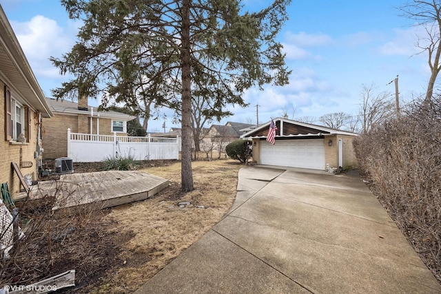 view of yard with cooling unit, driveway, a garage, and fence