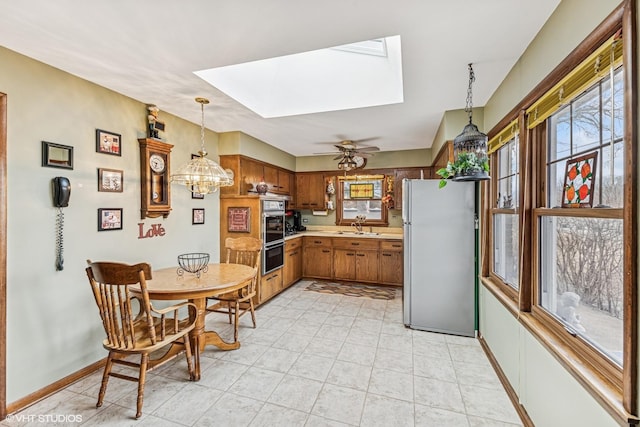 kitchen with a sink, a wealth of natural light, light countertops, and freestanding refrigerator