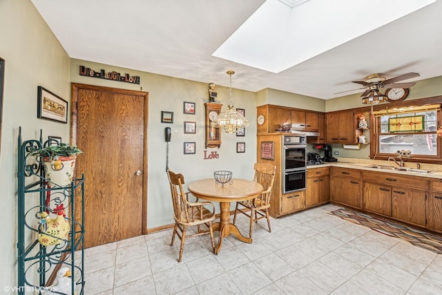 kitchen featuring light countertops, a skylight, brown cabinetry, dobule oven black, and a sink