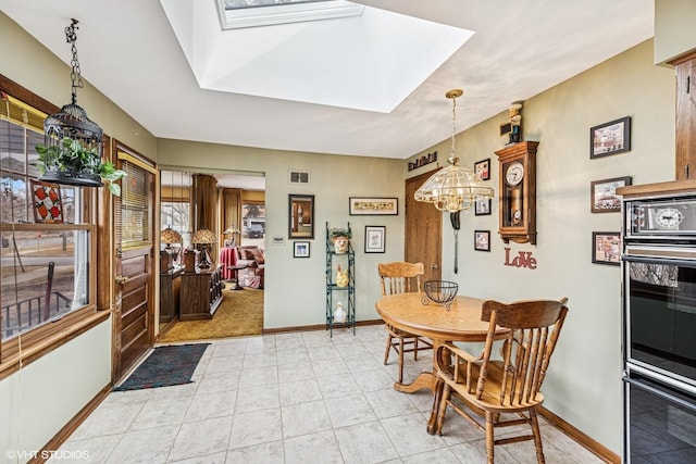 dining space with a skylight, light tile patterned flooring, baseboards, and visible vents