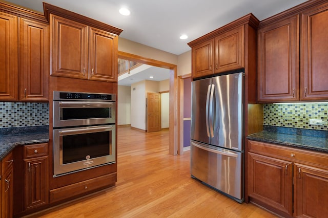 kitchen featuring light wood finished floors, brown cabinetry, stainless steel appliances, backsplash, and recessed lighting