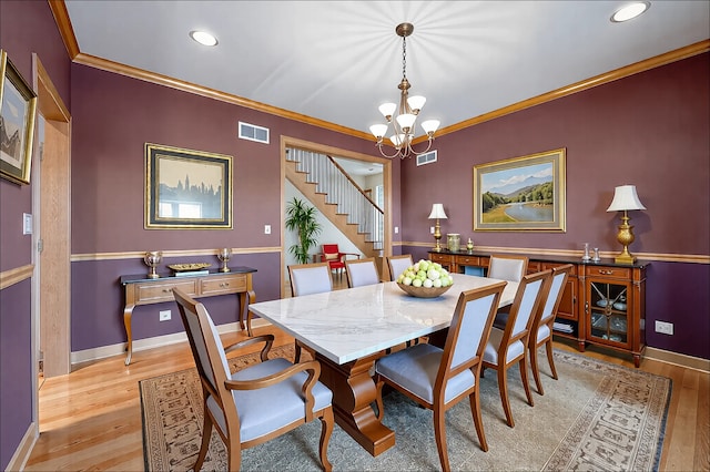 dining area with ornamental molding, visible vents, light wood finished floors, and an inviting chandelier