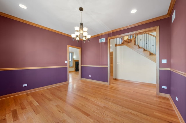 spare room featuring baseboards, visible vents, wood finished floors, stairs, and crown molding