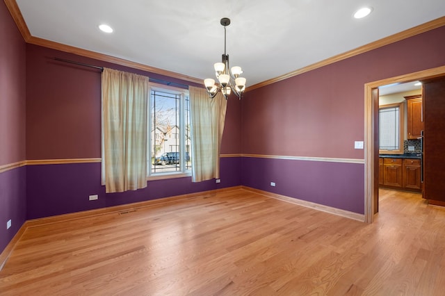 empty room with ornamental molding, light wood finished floors, an inviting chandelier, and baseboards