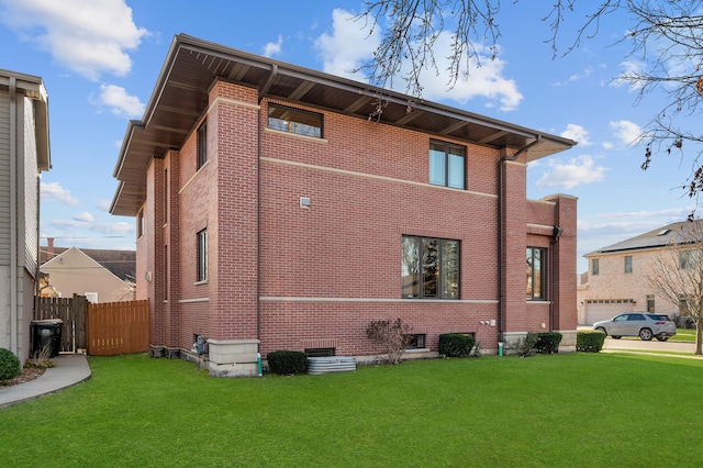 back of house with a yard, brick siding, and fence