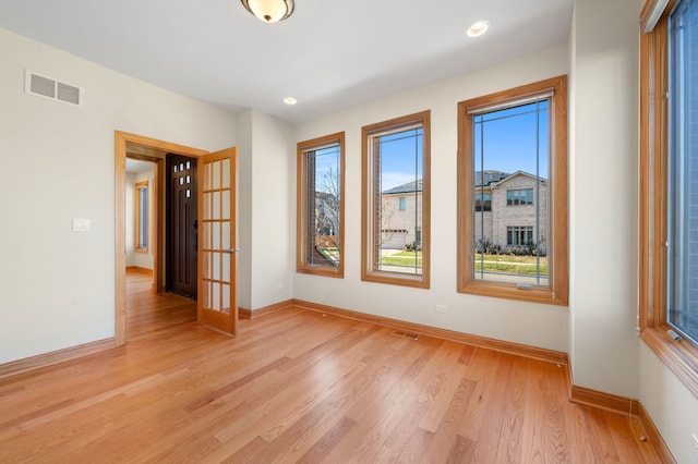 spare room featuring light wood-type flooring, visible vents, baseboards, and recessed lighting