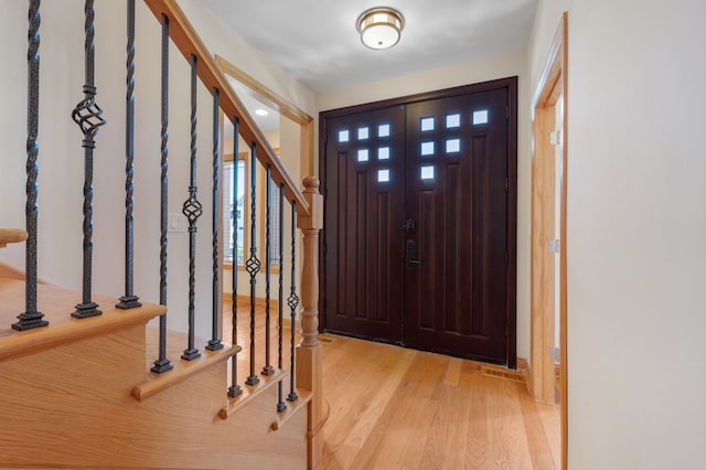 entrance foyer featuring stairs, a wealth of natural light, and light wood-style flooring