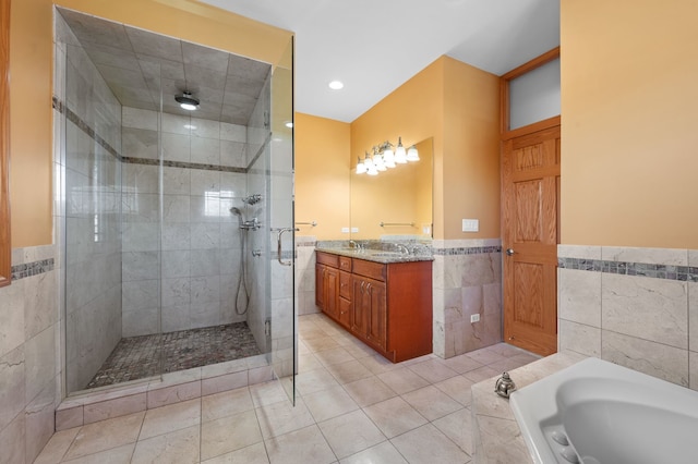 bathroom with tile patterned flooring, vanity, tile walls, a bath, and a stall shower