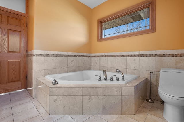 bathroom with toilet, a garden tub, tile patterned flooring, and tile walls