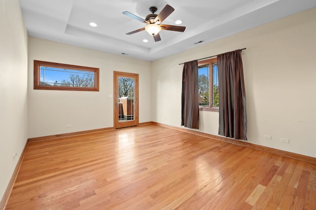 unfurnished room with visible vents, baseboards, a raised ceiling, light wood-style floors, and recessed lighting