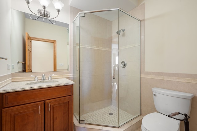 bathroom featuring a stall shower, tile walls, toilet, and vanity