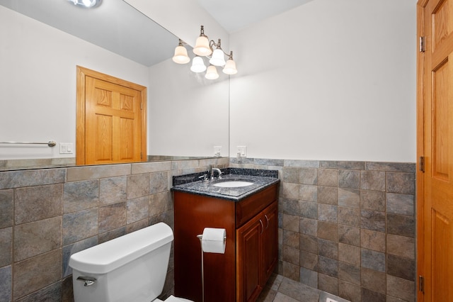 half bath featuring wainscoting, vanity, toilet, and tile walls