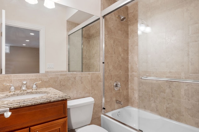 bathroom with toilet, enclosed tub / shower combo, tile walls, and vanity