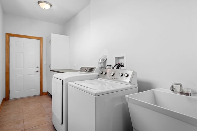 laundry area featuring cabinet space, light tile patterned flooring, a sink, and separate washer and dryer