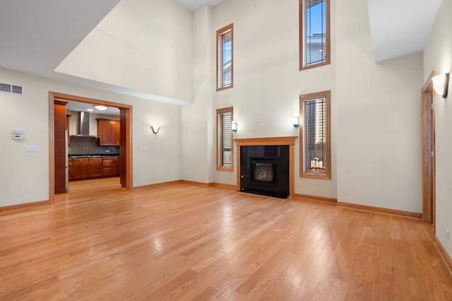 unfurnished living room featuring visible vents, a fireplace, light wood-style flooring, and a healthy amount of sunlight