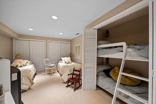 bedroom with multiple closets, recessed lighting, light colored carpet, and visible vents