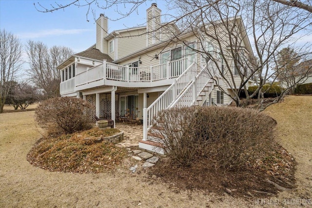 view of property exterior with a chimney, stairway, and a wooden deck