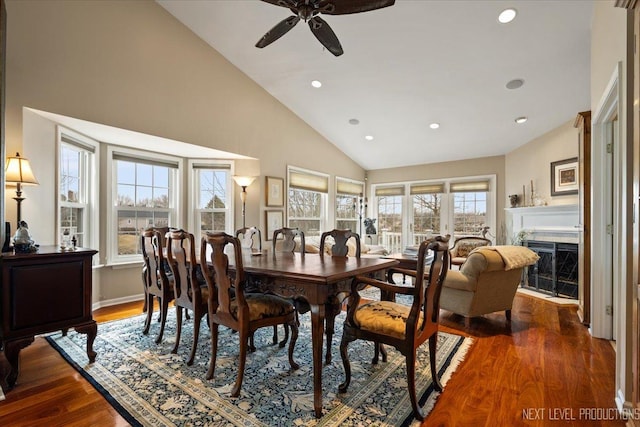 dining room with a high end fireplace, ceiling fan, wood finished floors, high vaulted ceiling, and recessed lighting