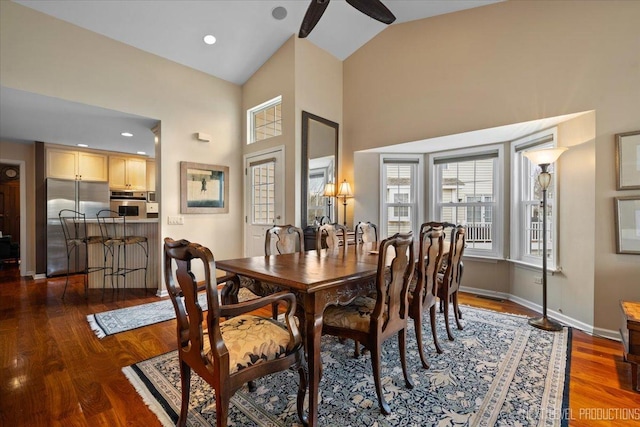 dining area featuring high vaulted ceiling, baseboards, and wood finished floors