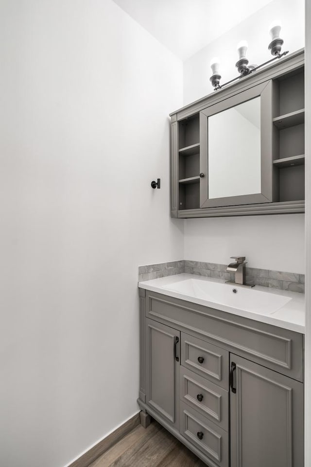 bathroom with baseboards, wood finished floors, and vanity