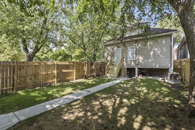 view of yard featuring entry steps, a fenced backyard, and central AC