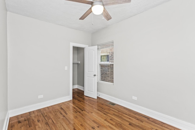 spare room with visible vents, baseboards, ceiling fan, wood finished floors, and a textured ceiling