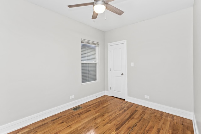 empty room featuring a ceiling fan, wood finished floors, visible vents, and baseboards