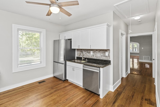 kitchen featuring visible vents, appliances with stainless steel finishes, a sink, white cabinetry, and backsplash