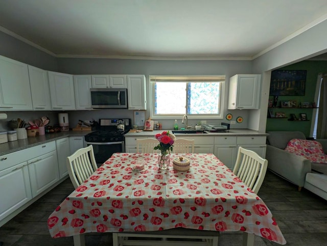 kitchen featuring appliances with stainless steel finishes, white cabinets, crown molding, and a sink