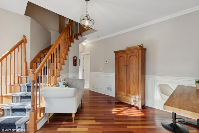 interior space featuring a decorative wall, a wainscoted wall, wood finished floors, visible vents, and crown molding