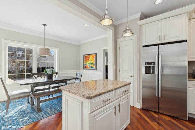 kitchen with light stone countertops, ornamental molding, stainless steel refrigerator with ice dispenser, and pendant lighting