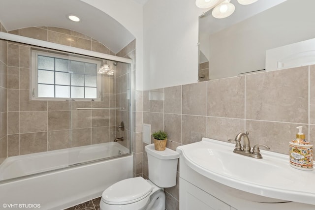 bathroom with enclosed tub / shower combo, toilet, vanity, and tile walls