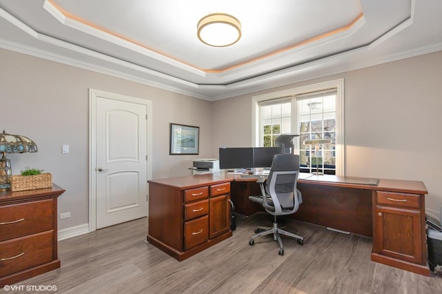 office area featuring a raised ceiling, crown molding, baseboards, and wood finished floors