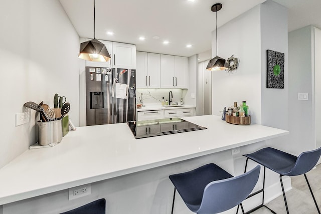 kitchen featuring a peninsula, a kitchen breakfast bar, a sink, and stainless steel fridge with ice dispenser