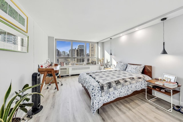 bedroom with radiator heating unit, a city view, and wood finished floors