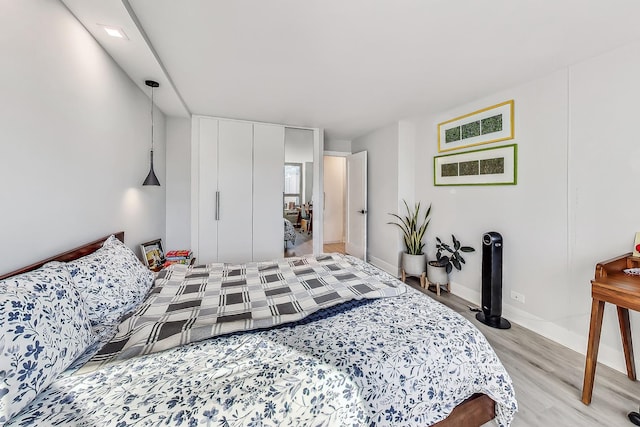 bedroom with a closet, baseboards, and light wood finished floors