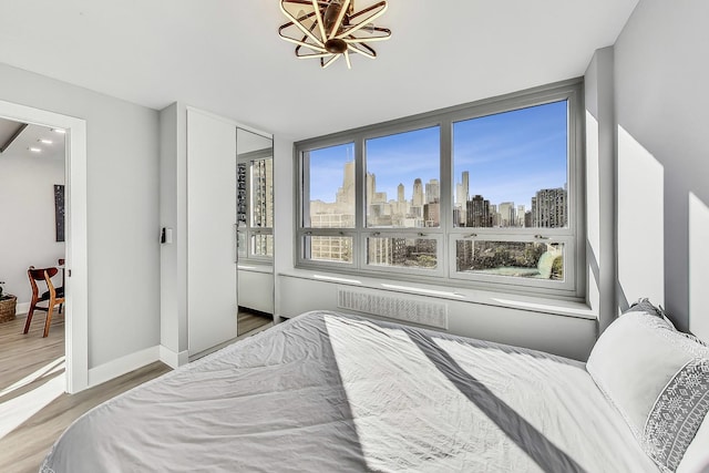 bedroom with a view of city, visible vents, baseboards, and wood finished floors