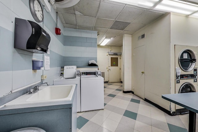 kitchen with light floors, visible vents, stacked washer / dryer, a sink, and independent washer and dryer