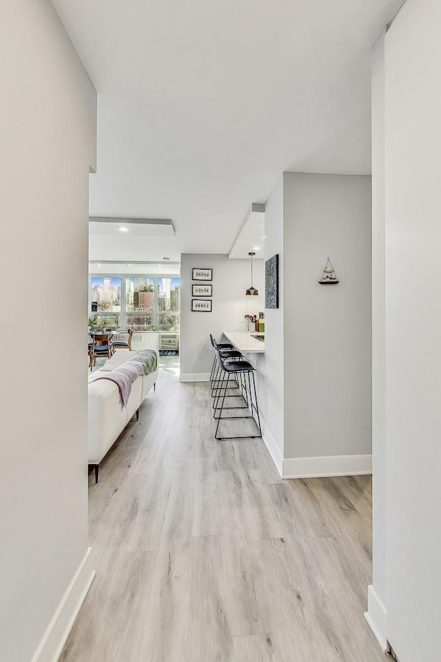 corridor featuring light wood-type flooring and baseboards