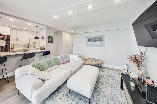 living area with light wood-style floors, baseboards, and recessed lighting