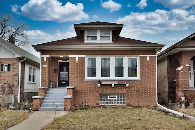 bungalow with a front lawn, fence, and brick siding