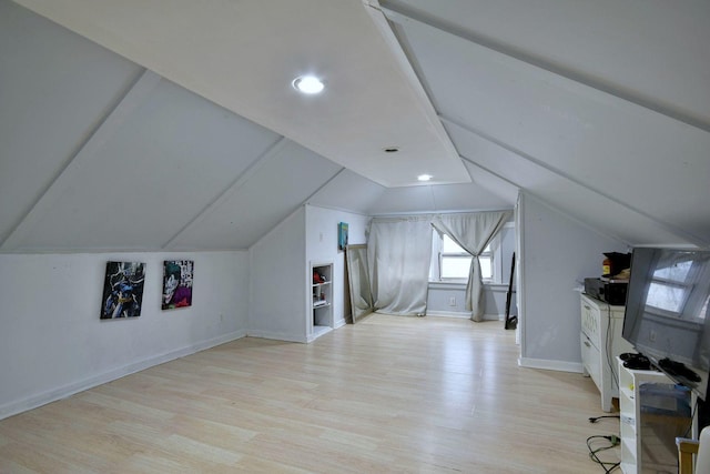 additional living space with light wood finished floors, baseboards, and vaulted ceiling