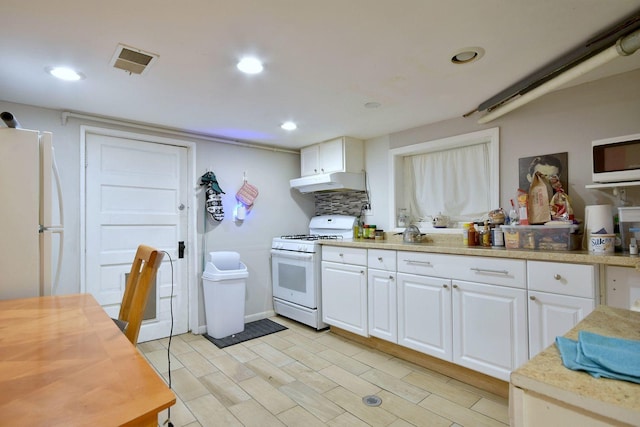 kitchen featuring white appliances, under cabinet range hood, visible vents, and white cabinets