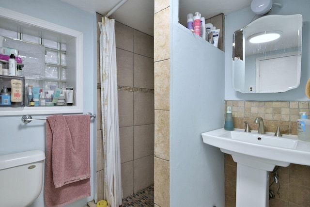 bathroom with a tile shower, backsplash, and toilet