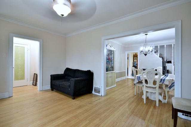 living area with crown molding, light wood finished floors, visible vents, a chandelier, and baseboards