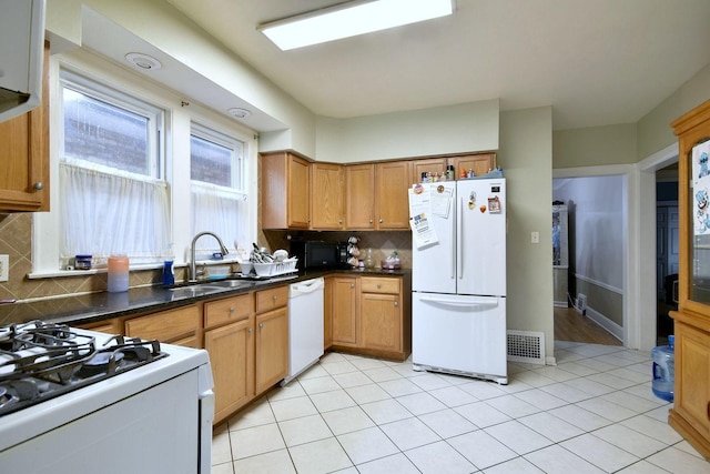 kitchen with white appliances, tasteful backsplash, visible vents, dark countertops, and a sink